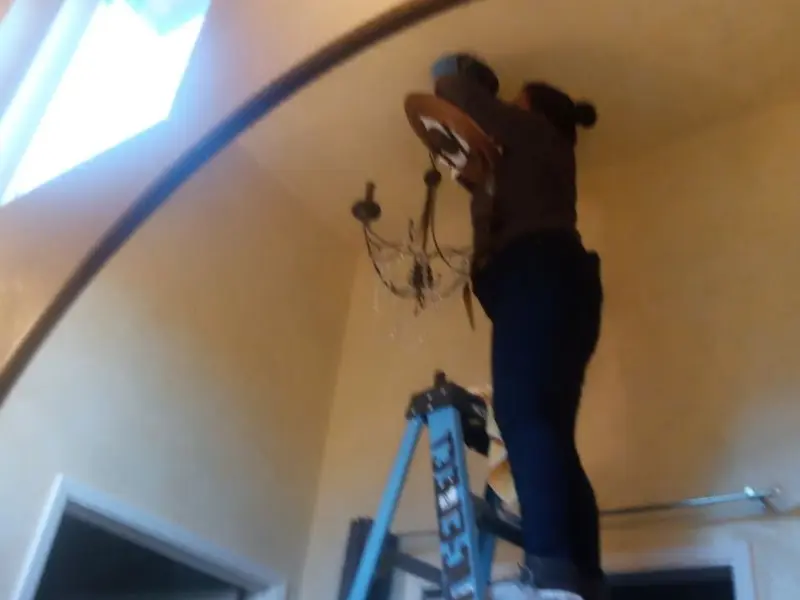 Electrician installing a chandelier in a Delaware residence